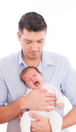 Vater haellt schreiendes Baby in der Hand